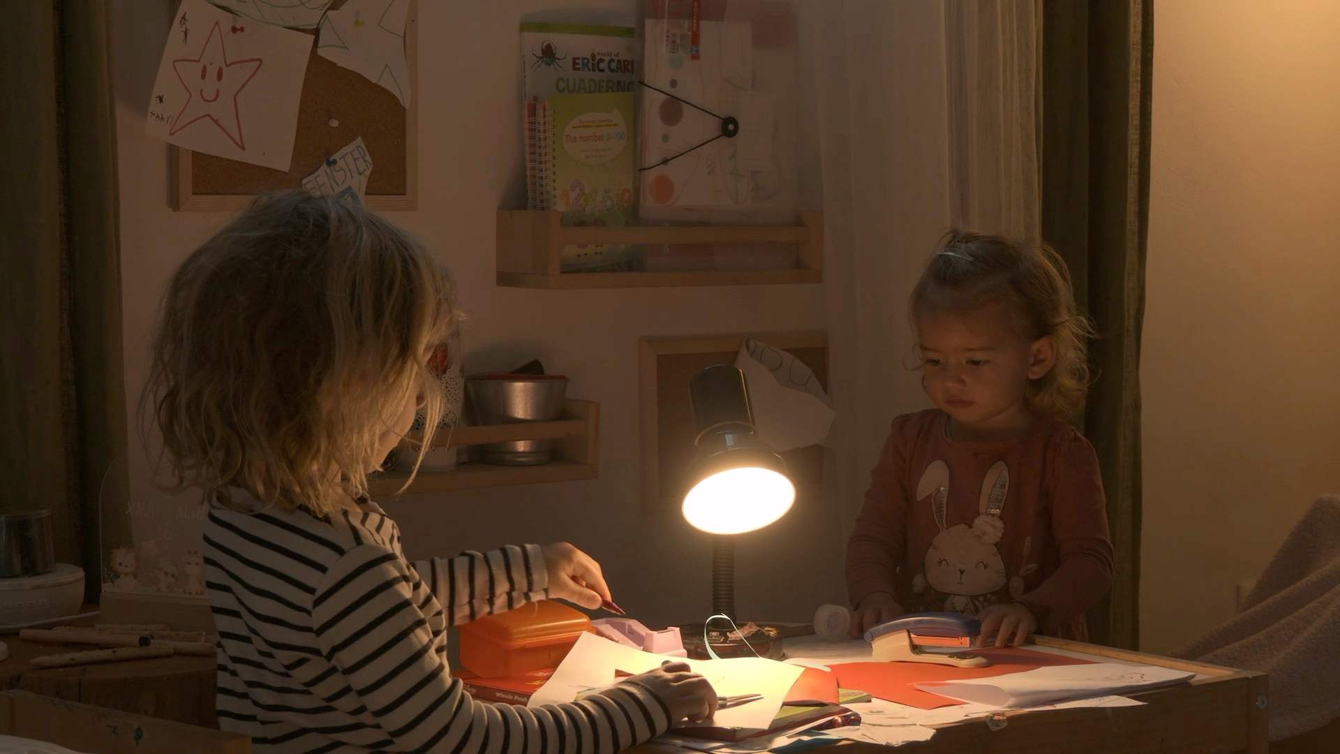 Die Kinder malen abends im Schein einer Lampe